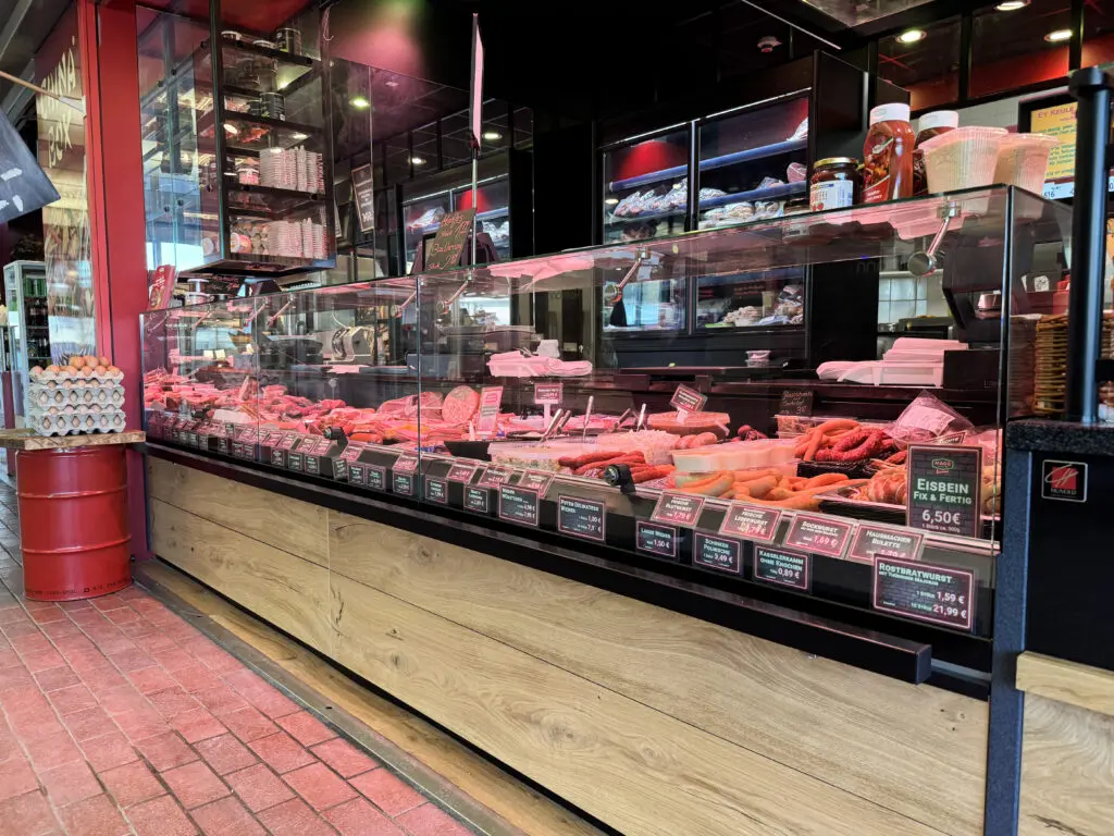 Fleischereitheke von MAGO im Märkischen Zentrum Berlin mit Holzfront, Glasaufsatz und übersichtlicher Warenpräsentation.