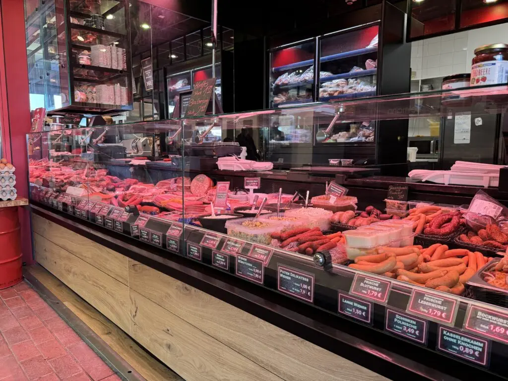 Detailansicht der Fleischtheke von MAGO im Märkischen Zentrum Berlin mit Wurstwaren, Glasaufsatz und Holzfront.
