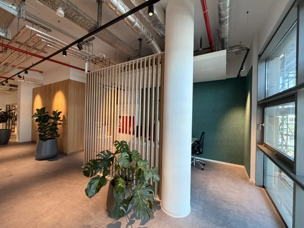 Abgeschirmter Arbeitsbereich der AOK Düsseldorf Stadtmitte mit Holzlamellen, Pflanzen und moderner Raumstruktur.