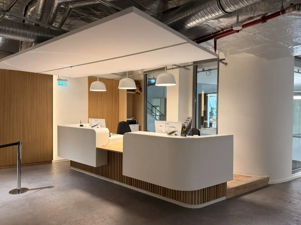Empfangsbereich im Zahnzentrum der AOK Düsseldorf Stadtmitte mit heller Empfangstheke, Holzlamellen und moderner Einrichtung.