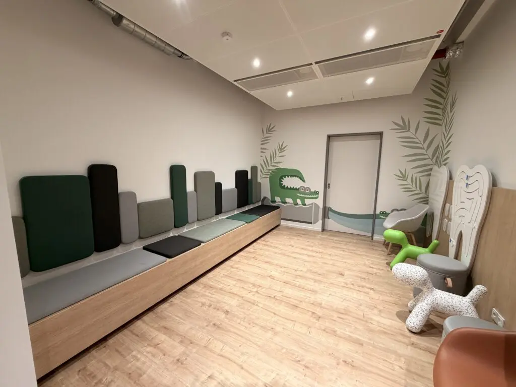 Kinderbereich im Zahnzentrum der AOK Düsseldorf Stadtmitte mit Sitzbank, kindgerechter Zahnvorsorge-Station und spielerischer Wandgestaltung.