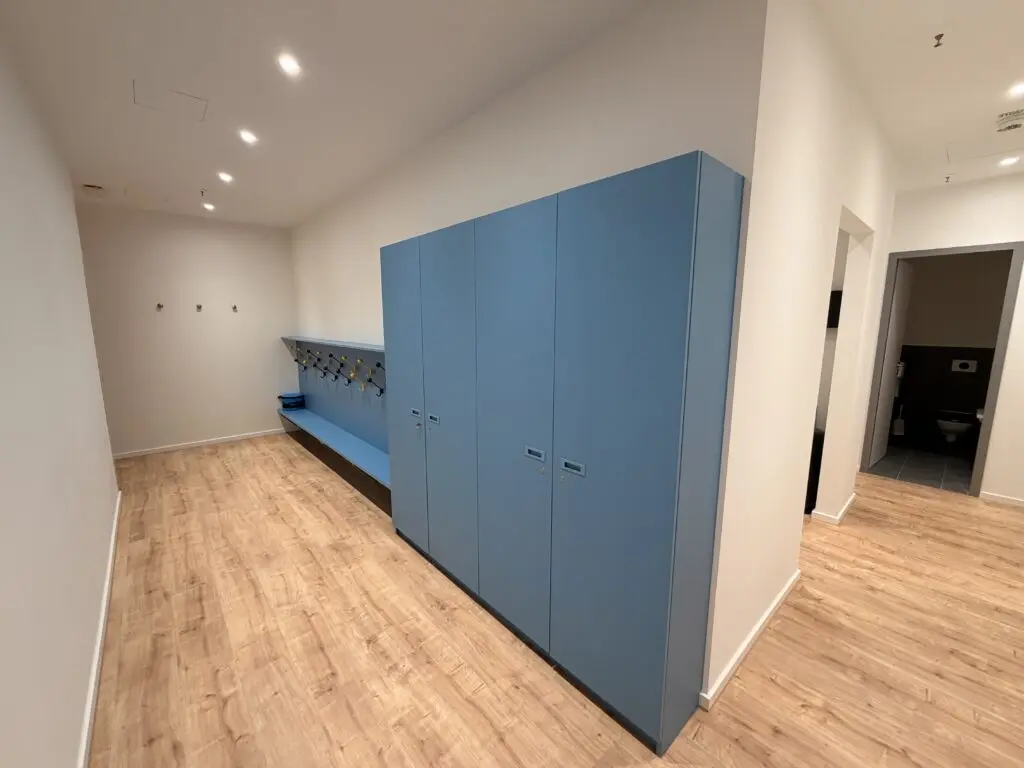 Garderobe im AOK U-Boot Gesundheitszentrum für Kinder mit blauen Schränken, Sitzbank und Hakenleiste.