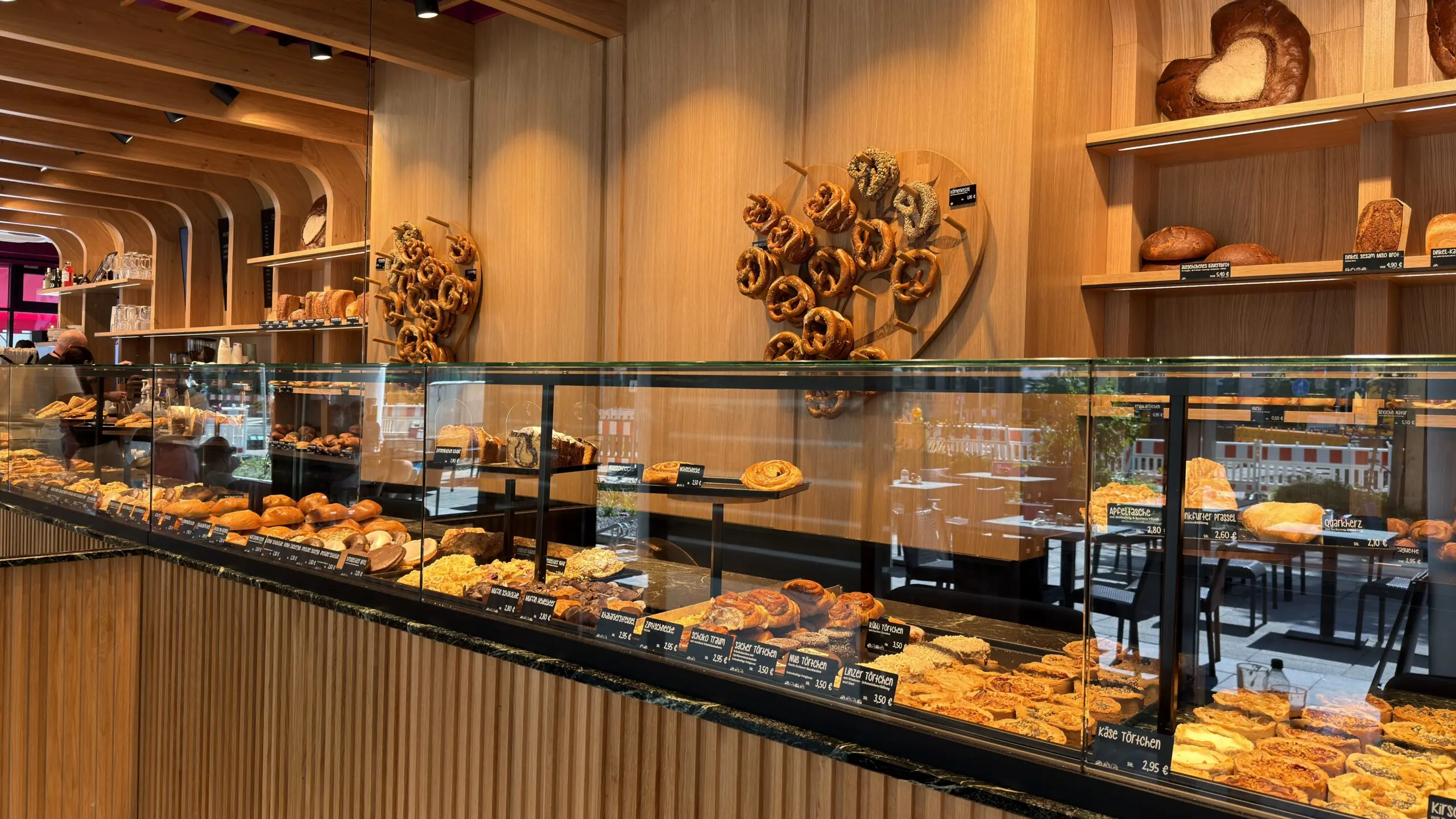Bäckereitheke der Bäckerei Huck in Frankfurt mit Spiegelwand, heller Holzoptik und Gebäck in der Auslage.