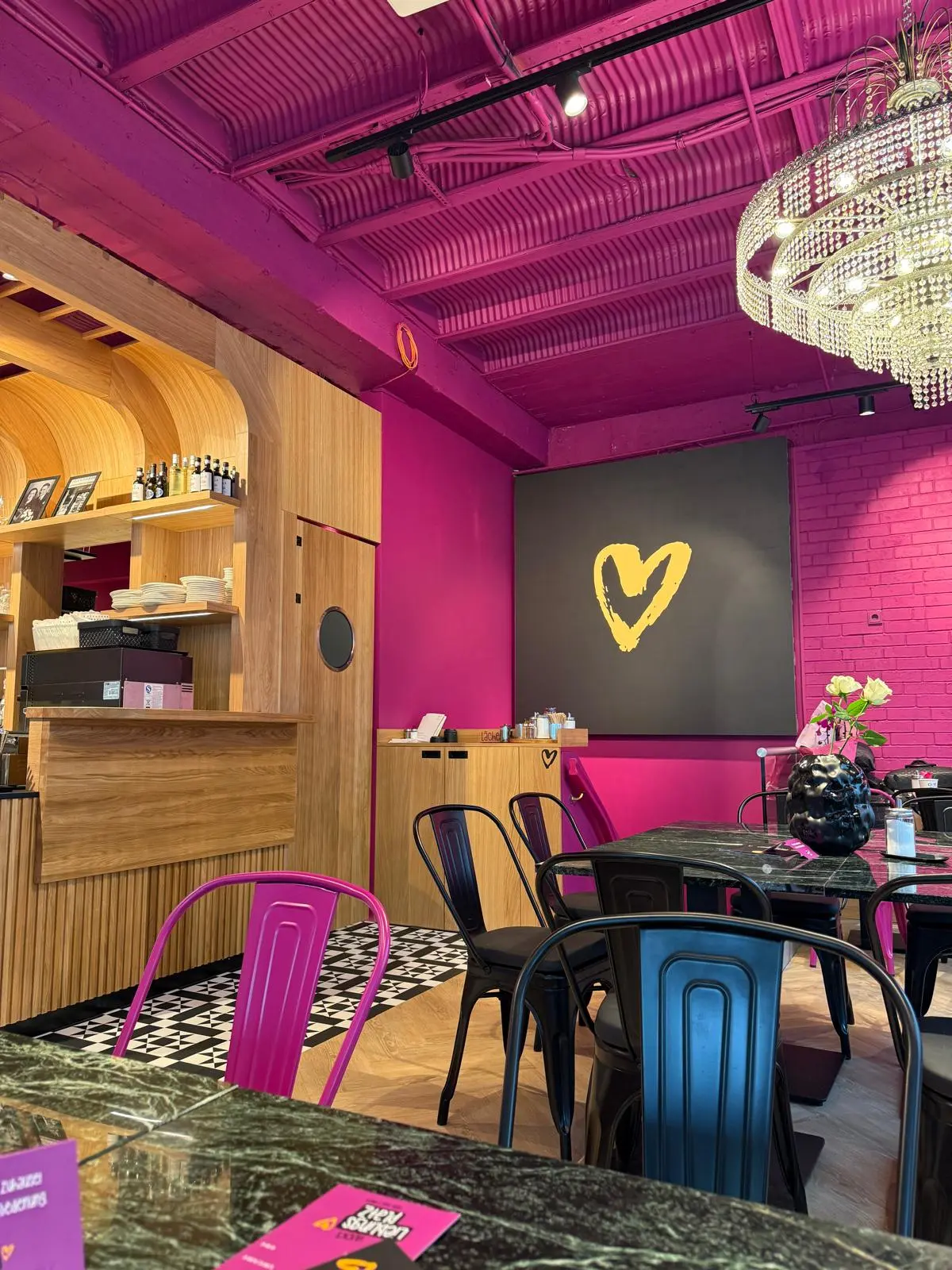 Sitzbereich der Bäckerei Huck in Frankfurt mit pinken Akzenten, großen Fenstern, Holztischen und gemütlichen Sitzplätzen.