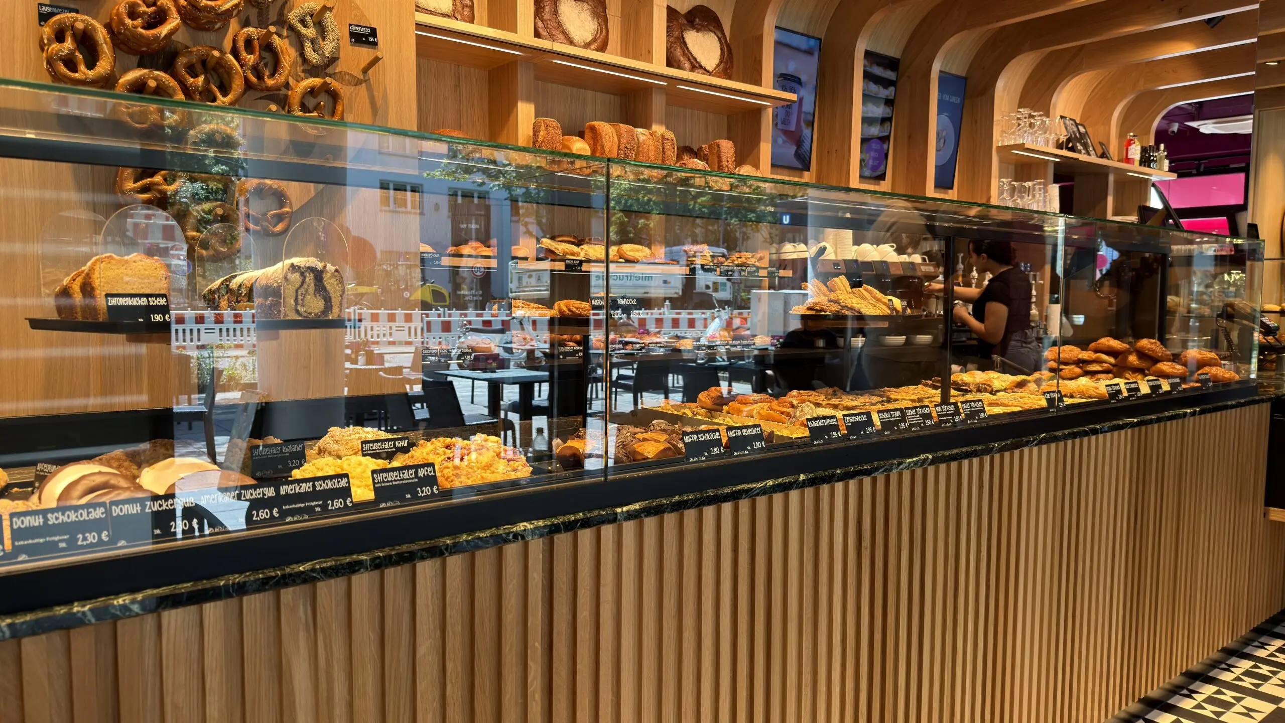 Trockene Bäckereitheke der Bäckerei Huck in Frankfurt mit Gebäckauslage, Glasaufsatz und heller Holzfront.