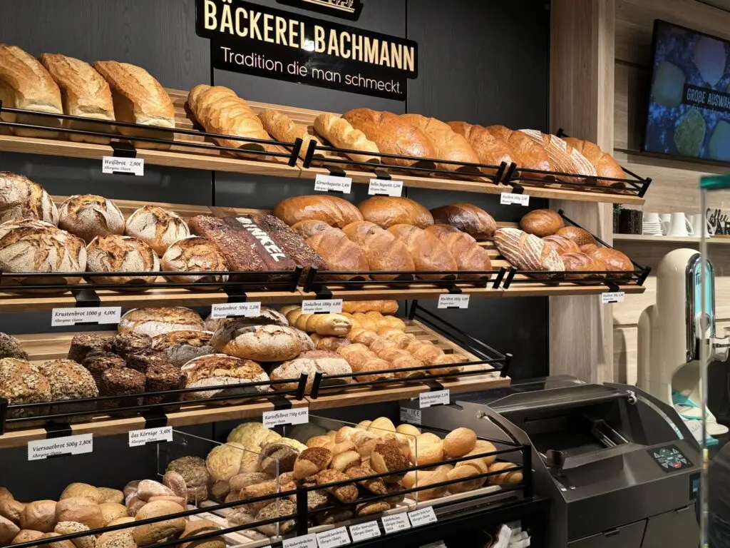 Bäckereieinrichtung der Bäckerei Bachmann in Küllstedt mit gefülltem Brotregal, Holzoptik und schwarzer Akzentgestaltung.