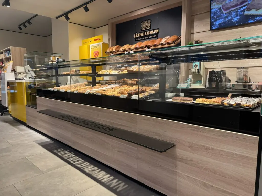 Verkaufstheke der Bäckerei Bachmann in Küllstedt mit Holzoptik, Backwaren und integriertem Brotregal im Hintergrund.