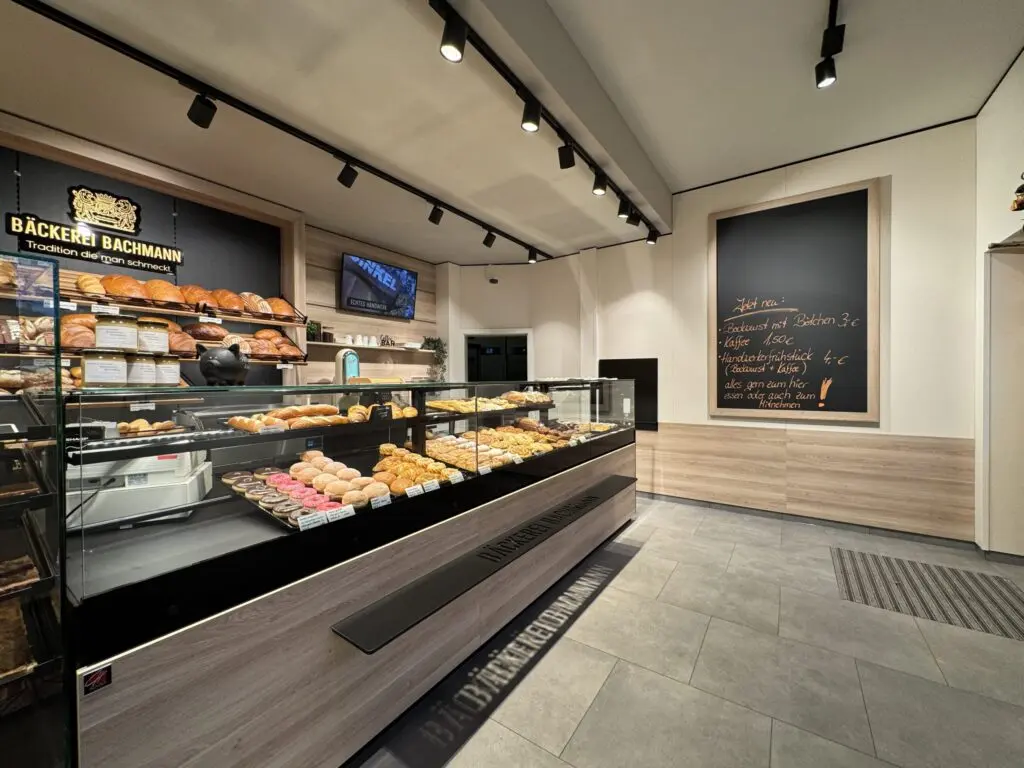 Verkaufstheke der Bäckerei Bachmann in Küllstedt mit Backwaren, Brotregal und Kreidetafel an der Wand.